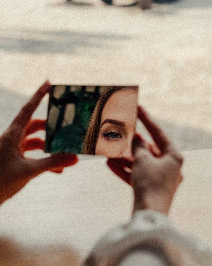 Woman in makeup looking in mirror in street